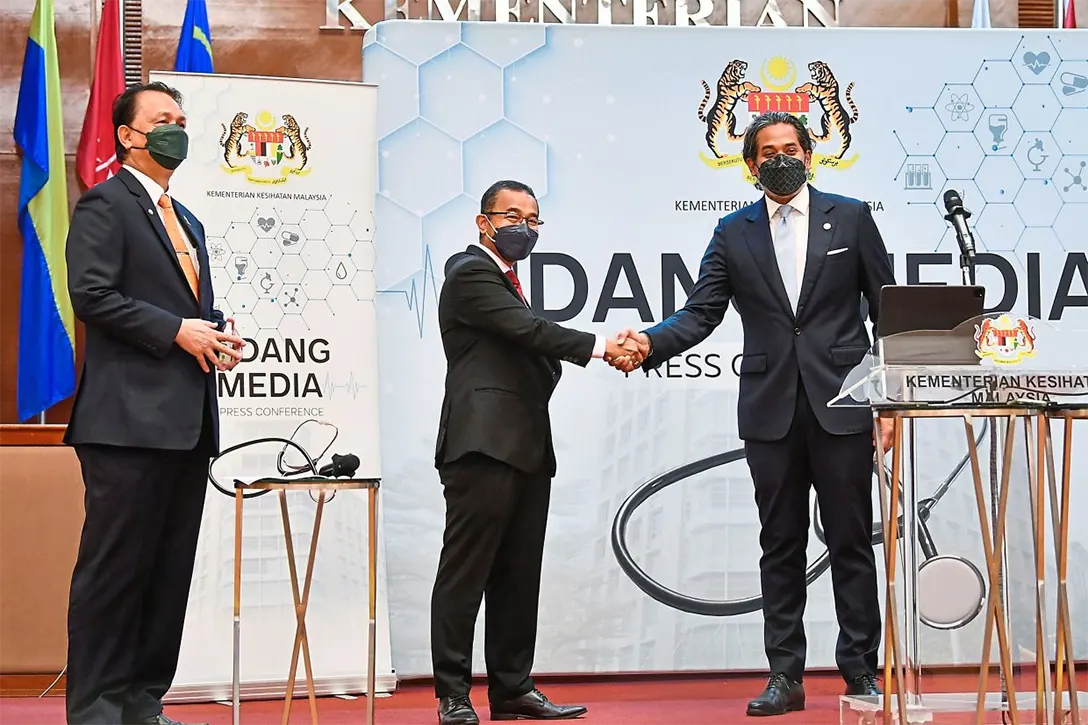 On a new direction: Khairy (right) greeting Dr Noor Azmi with a handshake while Dr Noor Hisham looks on at the press conference in Putrajaya. — Bernama